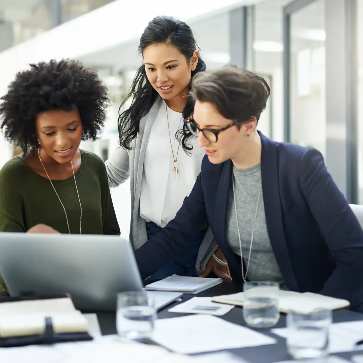 A group of business professionals collaborate on a project using a laptop, demonstrating teamwork and strategic planning in business management.